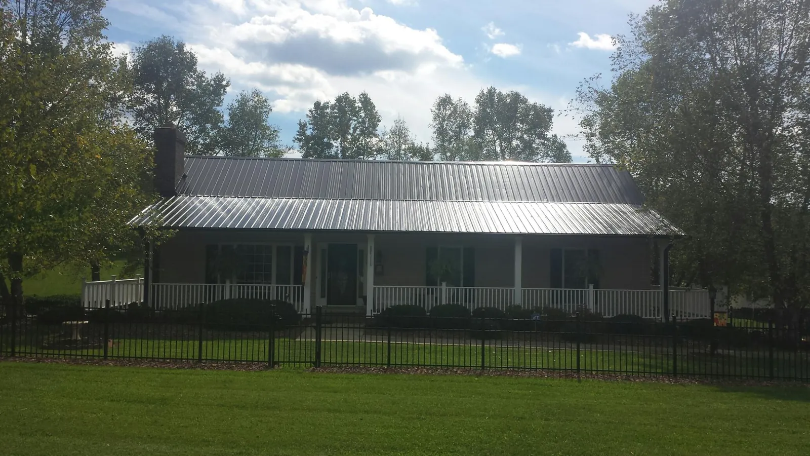 Gray metal roof on a brick ranch with a full width front porch — Gutter Guard Installation work by our crew in Sterling